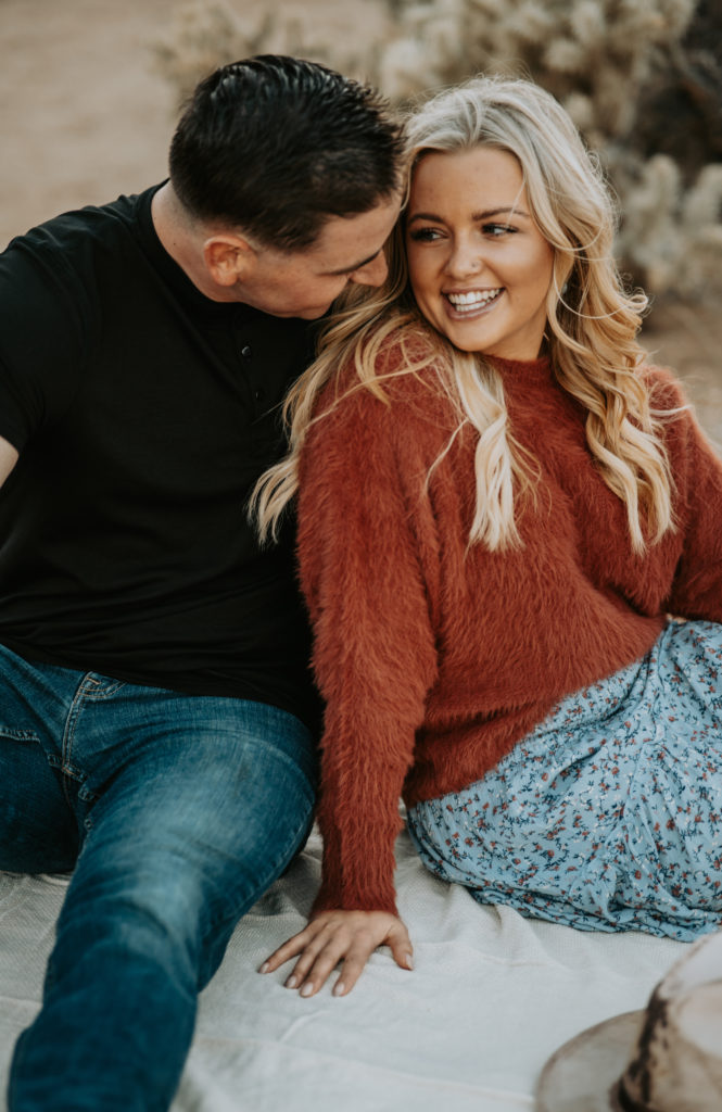 couple hugging on ground during engagement photoshoot in Joshua Tree
