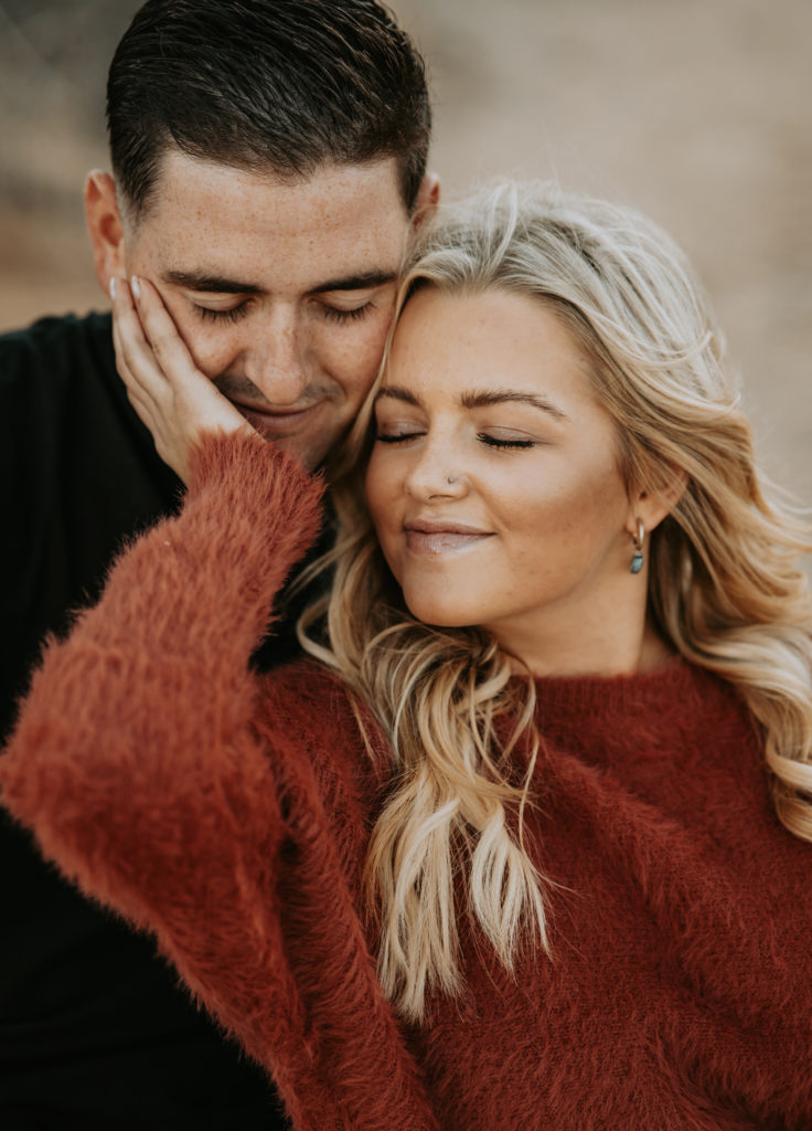 couple hugging on ground during engagement photoshoot in Joshua Tree