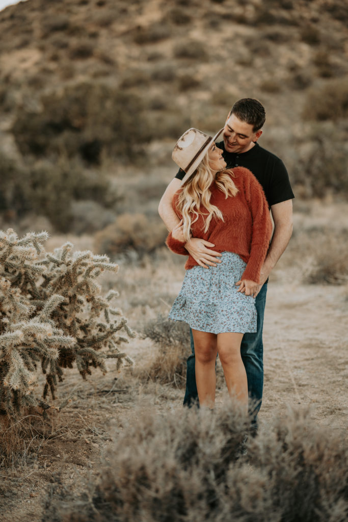 couple laying on ground looking at camera in joshua tree at engagement session