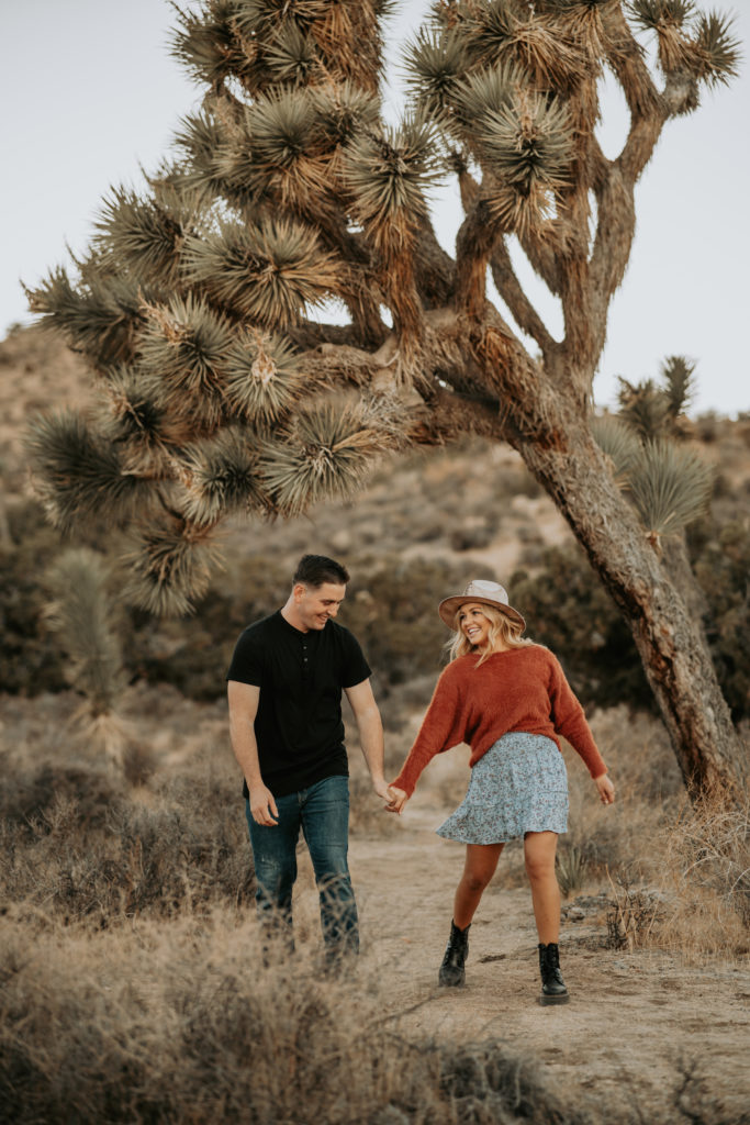 couple laying on ground looking at camera in joshua tree at engagement session