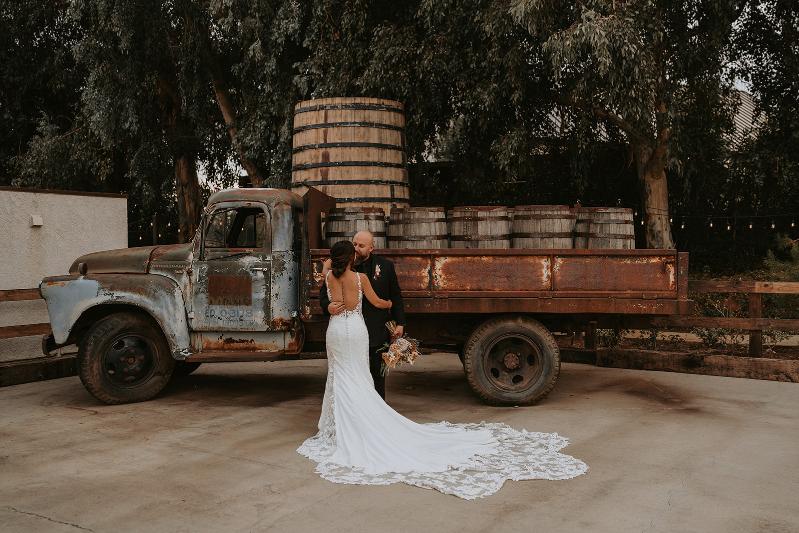 bride and groom posing near rustic old truck