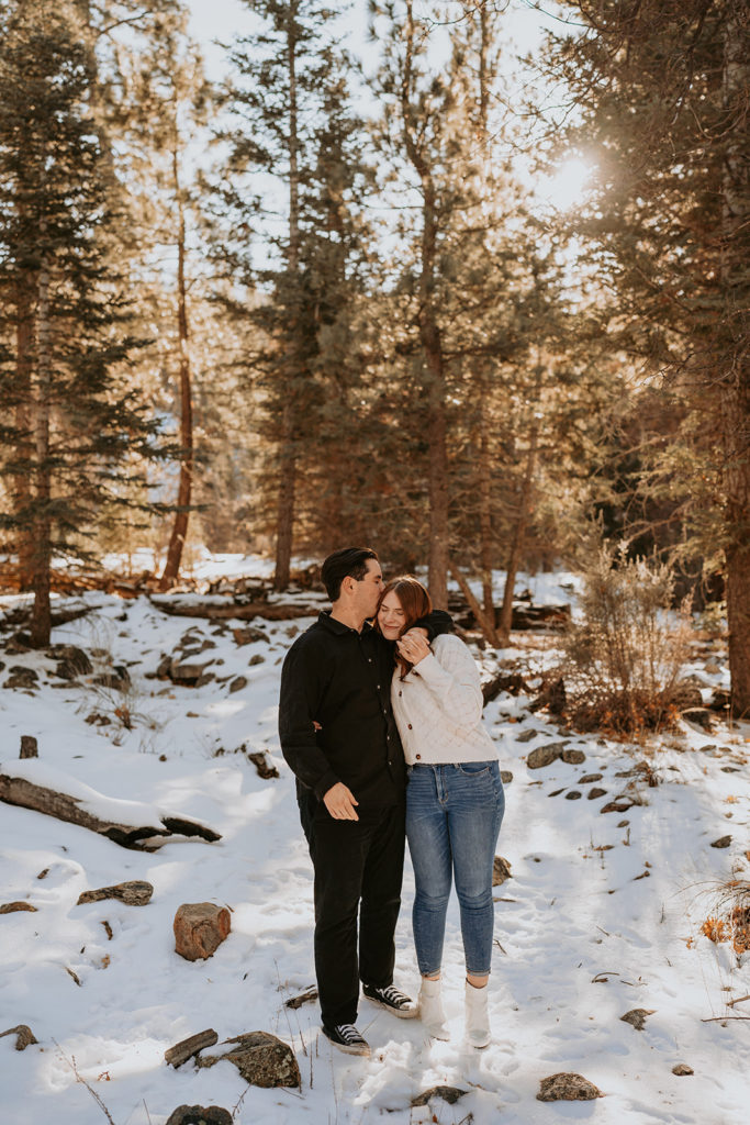 couple standing and posing for their snowy mountain engagement photos
