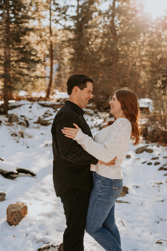 couple standing and posing for their snowy mountain engagement photos