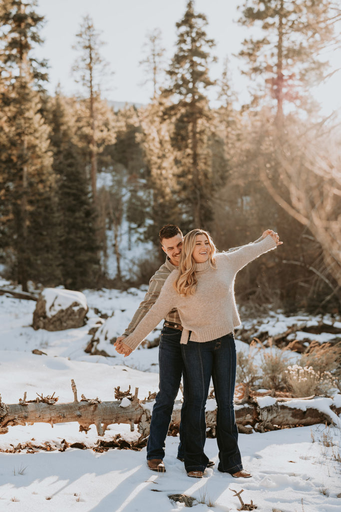 couple posing in the mountains for their couples photos with snow