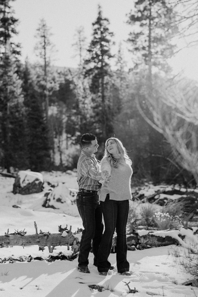 couple posing in the mountains for their couples photos with snow