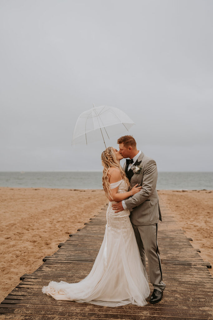 bride and groom posing for their wedding photos on the beach 