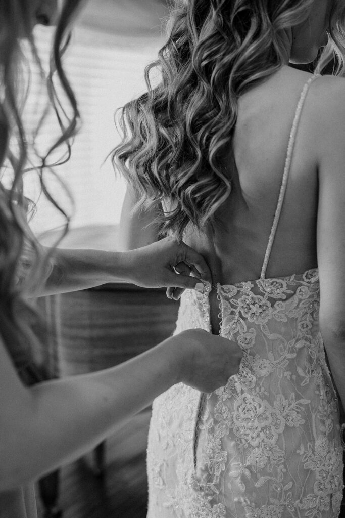 bride getting her dress zipped