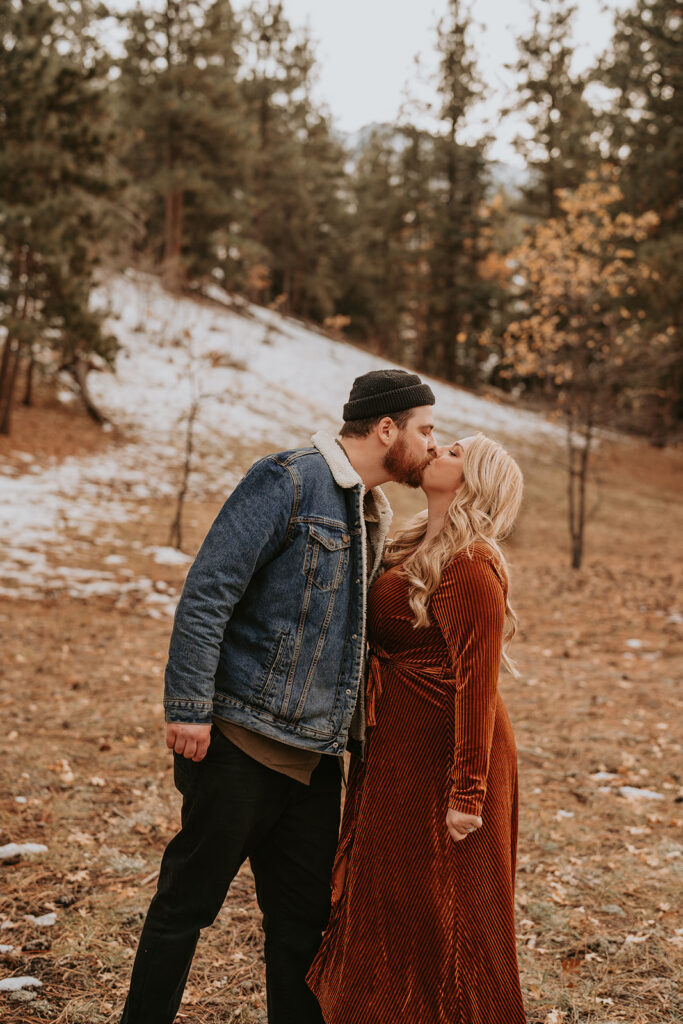 couple kissing for fall or winter mountain engagement session