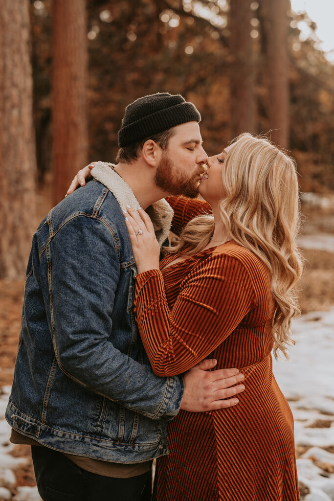 Engagement couple kissing in the winter mountains
