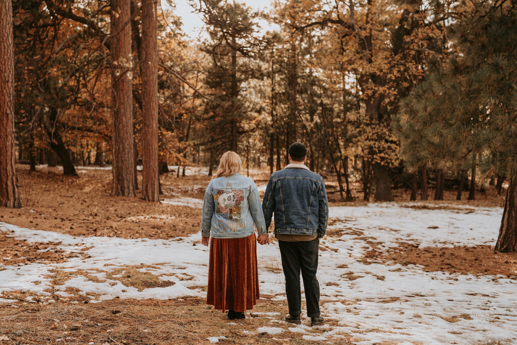 Couple standing among trees for a mountain winter engagement session