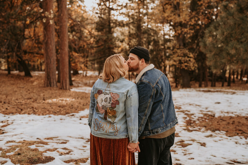 Couple kissing among trees for a mountain winter engagement session