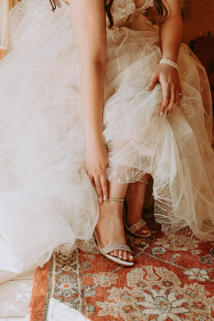 women in a wedding dress putting on shoes