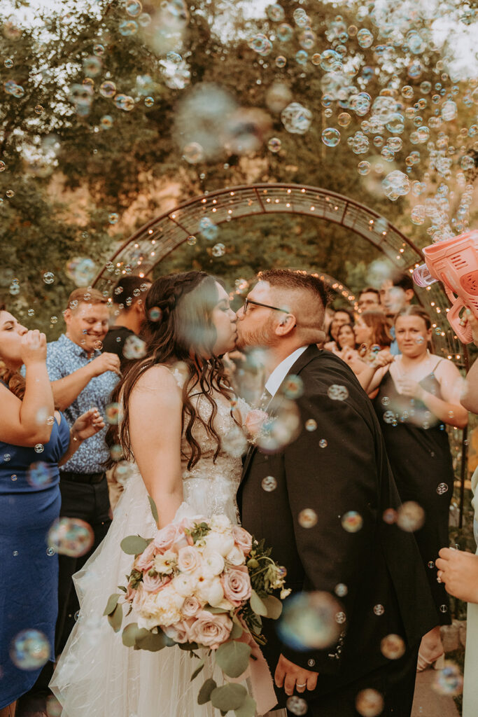 Bride and Groom kissing with bubbles during a wedding exit