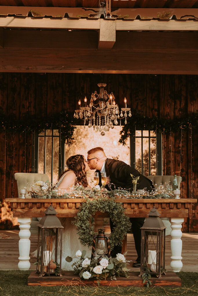 bride and groom with wedding florals at the head table