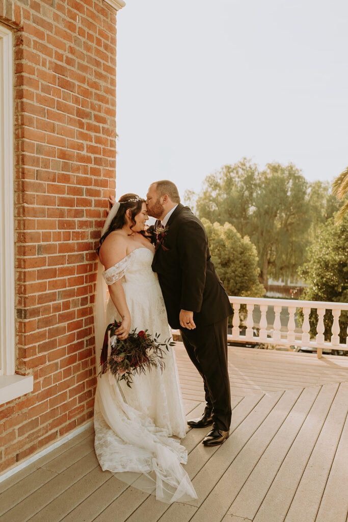 bride and groom in front of a large brick home