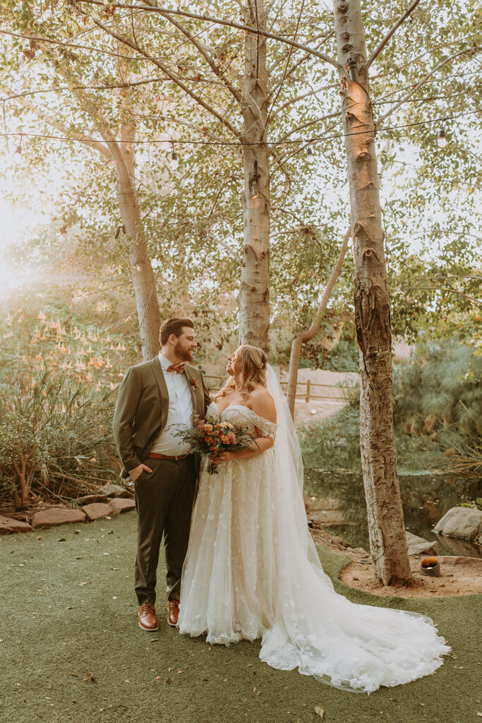bride and groom standing among trees