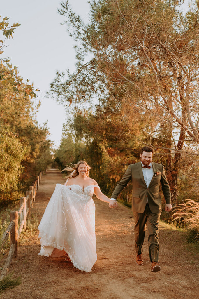 bride and groom running along a path among trees