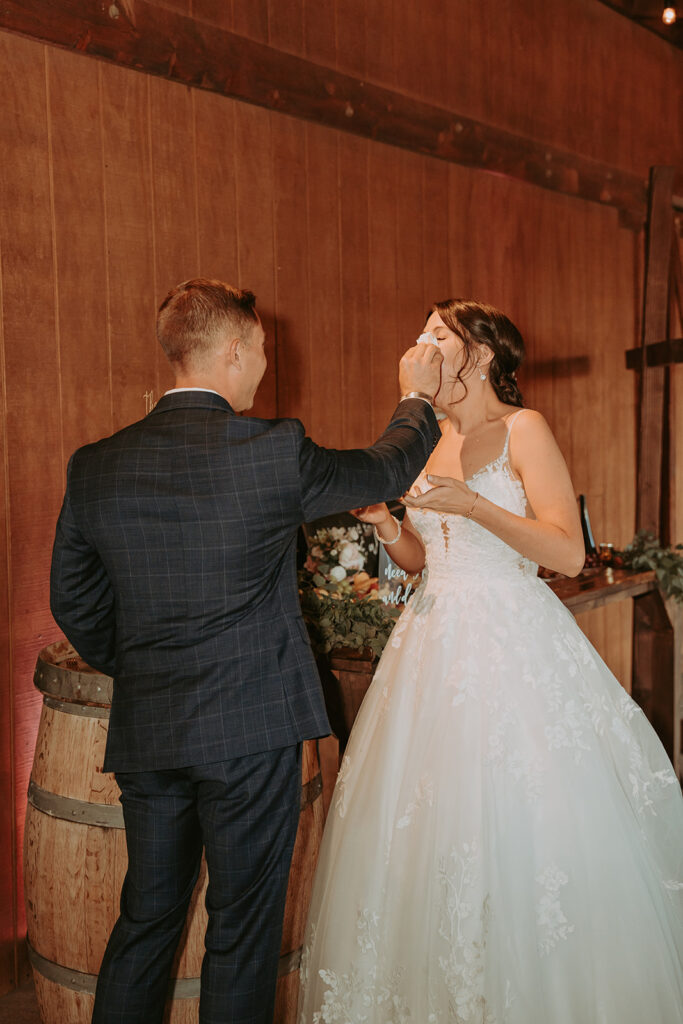 bride and groom cutting cake in a barn