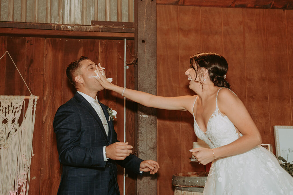 bride and groom cutting cake in a barn