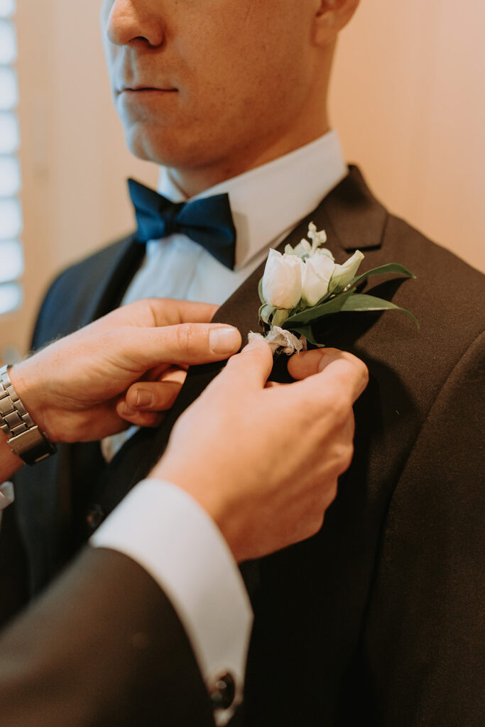 Someone pinning a boutonniere on a groom