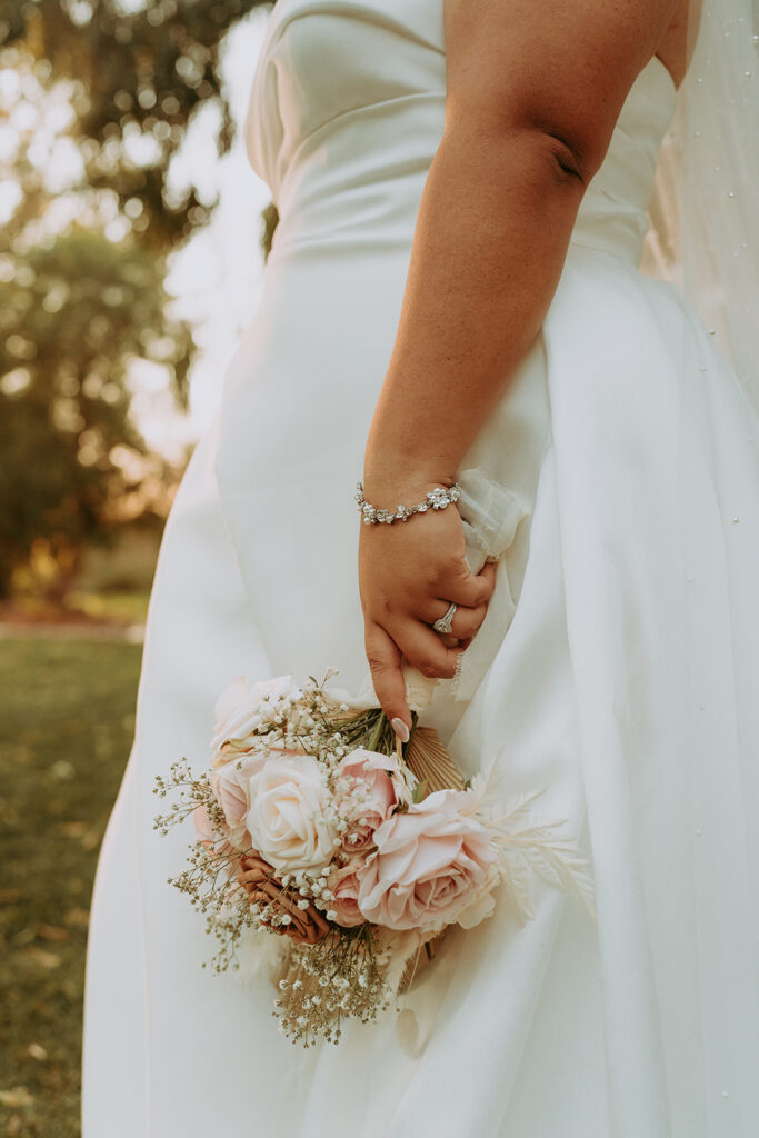 bride in her dress with a light pink rose bouquet