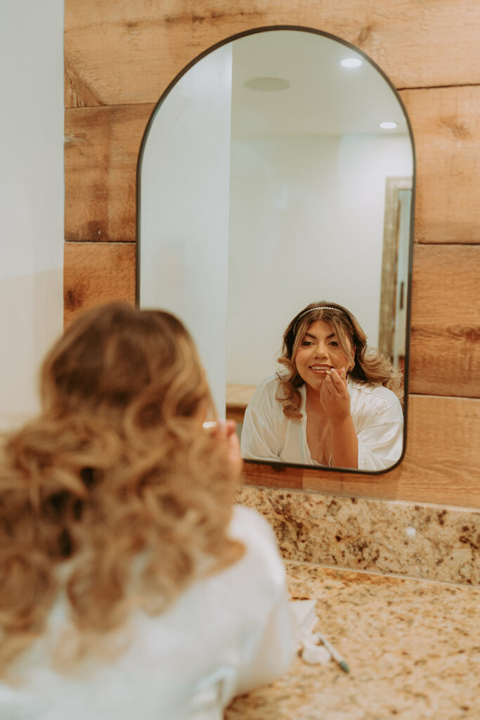 bride doing her makeup in a mirror