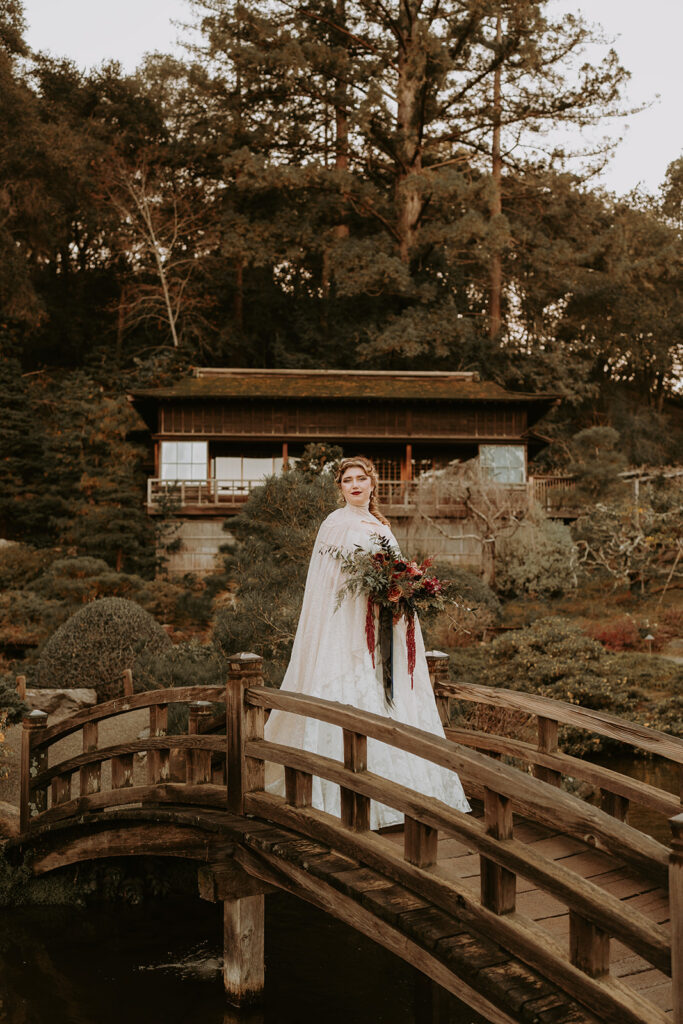 bride standing with her bouquet on a bridge. Moody wedding aesthetic