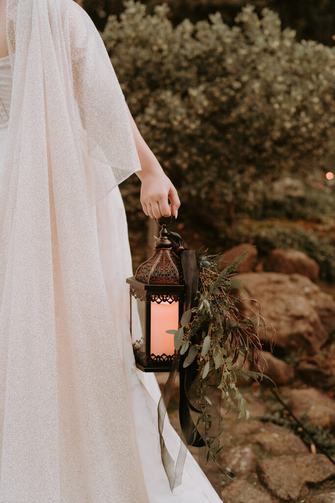 bride walking away from the camera with a lantern. moody wedding aesthetic