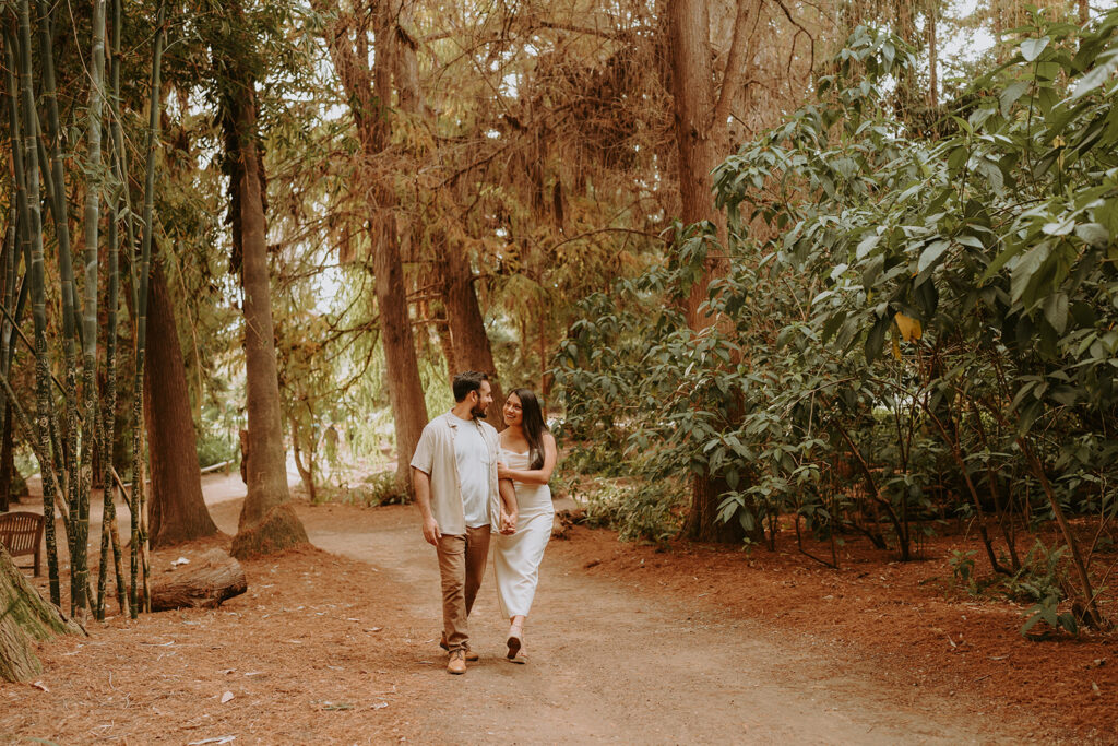 engaged couple smiling at each other for engagement photos at the Los Angeles arboretum