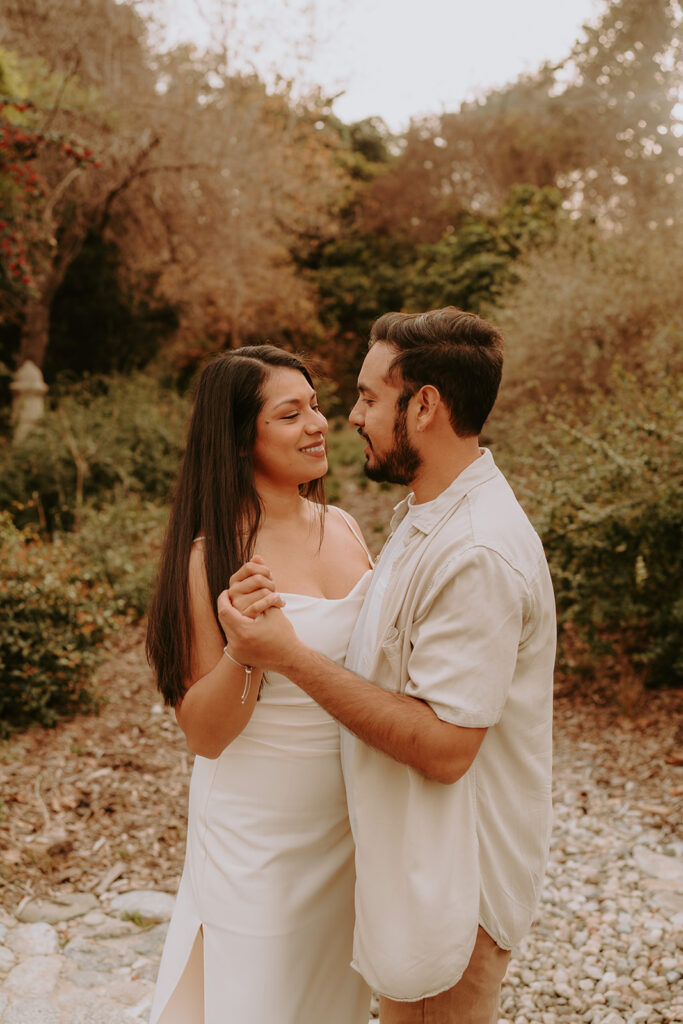engaged couple smiling at each other for engagement photos at the Los Angeles arboretum