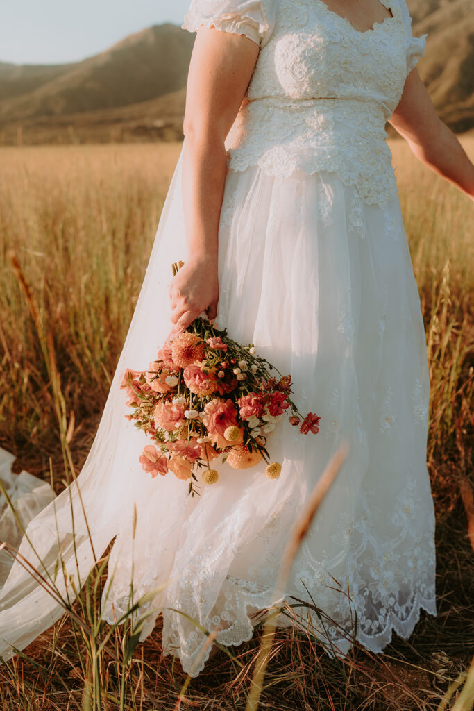 bride with wildflower bouquet in a field during sunset
