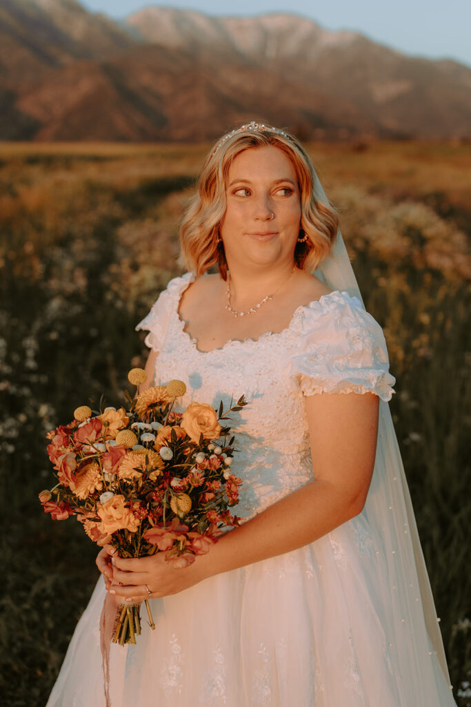 bride with wildflower bouquet in a field during sunset