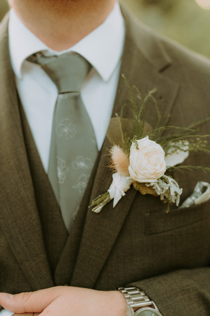 close up of a man in a suit with a corsage and floral tie