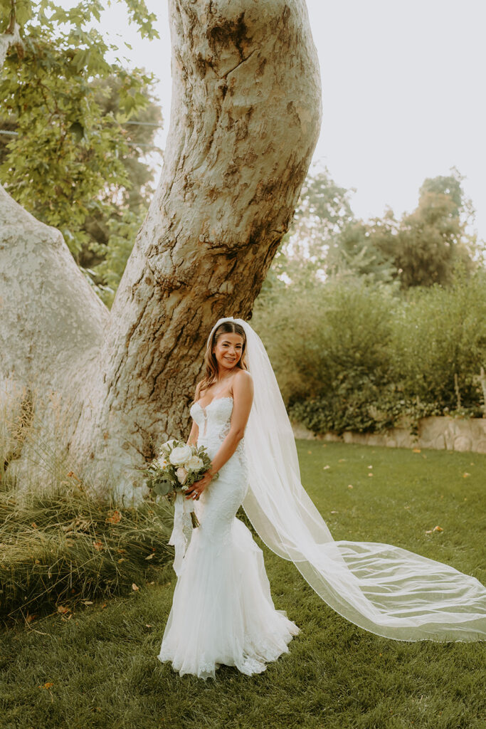 a bride posing near a large tree at an oak glen wedding venue