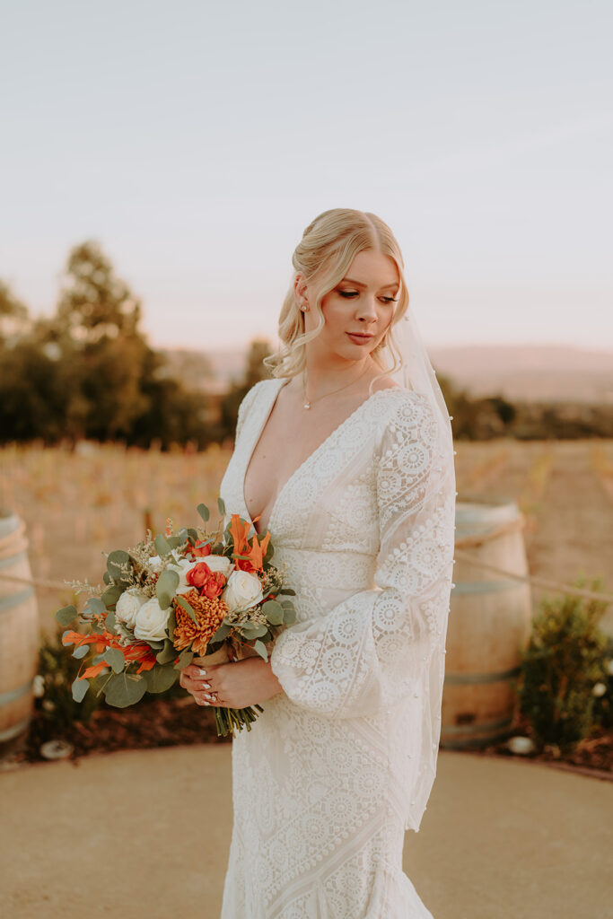 Rustic wedding decor with wine barrels and floral arrangements at Sacred Oak Vineyard in Cherry Valley.