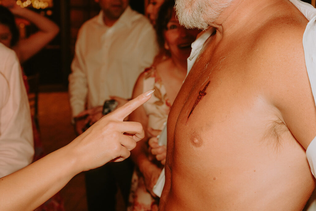 Candid photo of bride laughing after seeing her dad’s tattoo